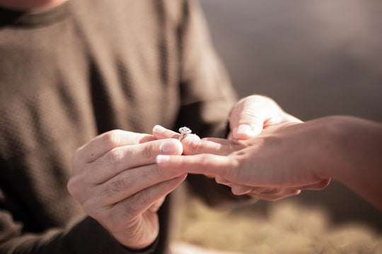 Close up of a man placing an engagement ring on a woman’s finger